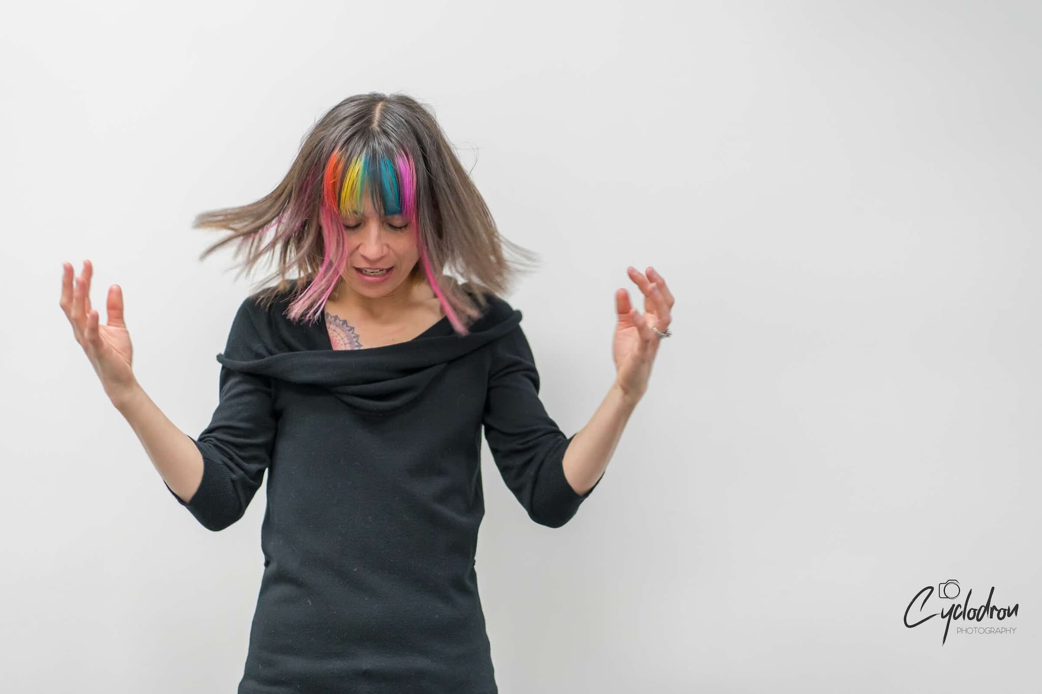 Dynamic studio portrait with rainbow-colored hair and motion